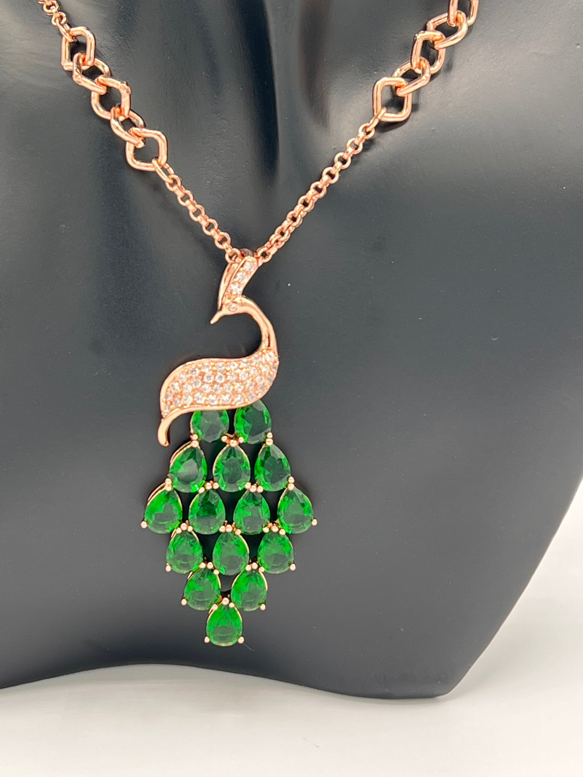 rose gold 70cm chain with peacock design  pendant. the peacock body is embellished with with cubic zircons and the feathers are made of big tear shaped green cubic zircons the link chain has small and big links which give this chain a unique look .