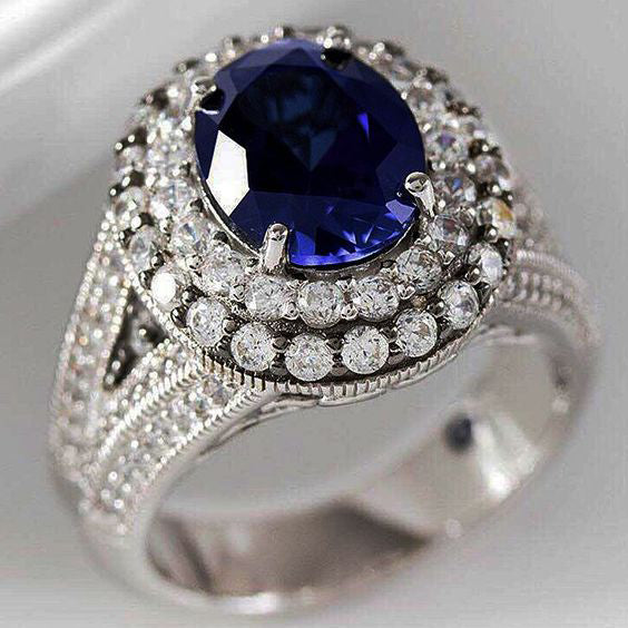 silver ring heavily embellished with white zircons the blue oval zircon is the middle stone